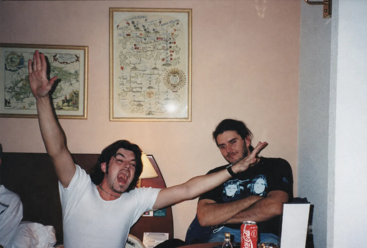 Two men larking about in a hotel room, one hand thrown in the air, 1990s